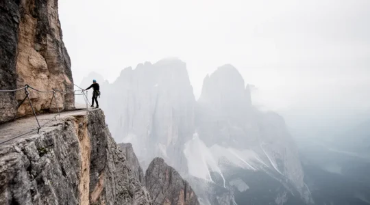 Escursionista su via ferrata nelle Dolomiti che affronta il vuoto con determinazione