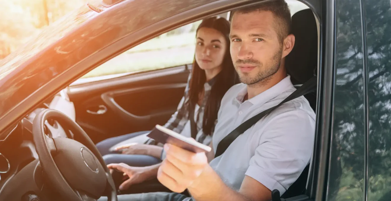 Una mano posa il voucher della prenotazione sul cruscotto dell'auto.